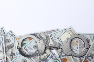 Photo of Corruption concept. Handcuffs and dollar banknotes on white background, top view