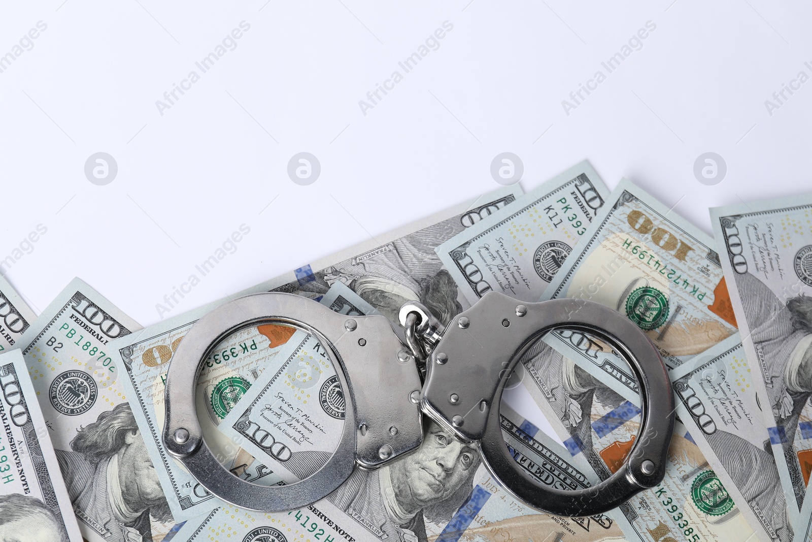 Photo of Corruption concept. Handcuffs and dollar banknotes on white background, top view