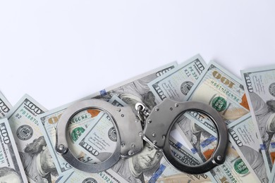 Photo of Corruption concept. Handcuffs and dollar banknotes on white background, top view