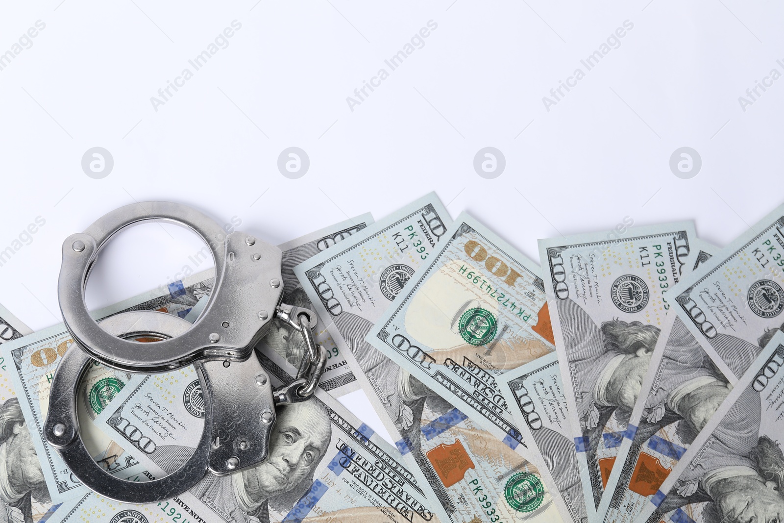 Photo of Corruption concept. Handcuffs and dollar banknotes on white background, top view