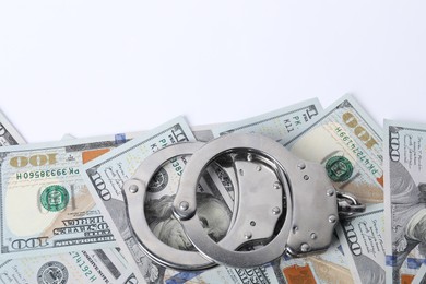 Photo of Corruption concept. Handcuffs and dollar banknotes on white background, top view