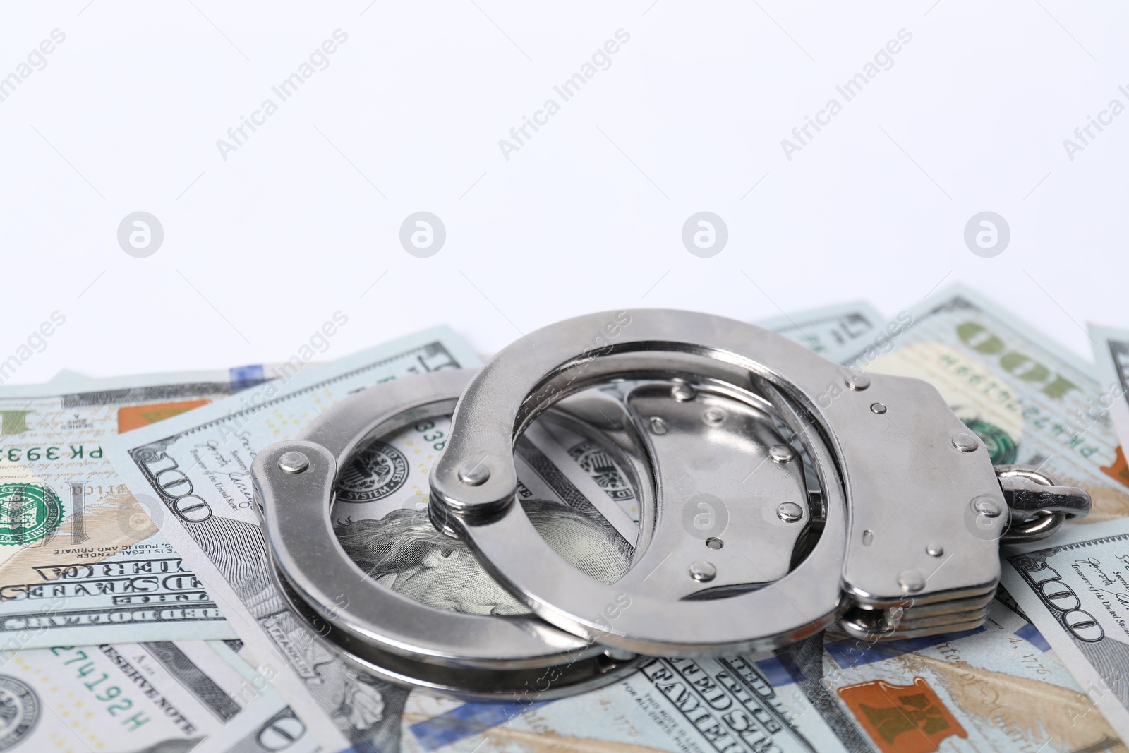 Photo of Corruption concept. Handcuffs and dollar banknotes on white background, closeup