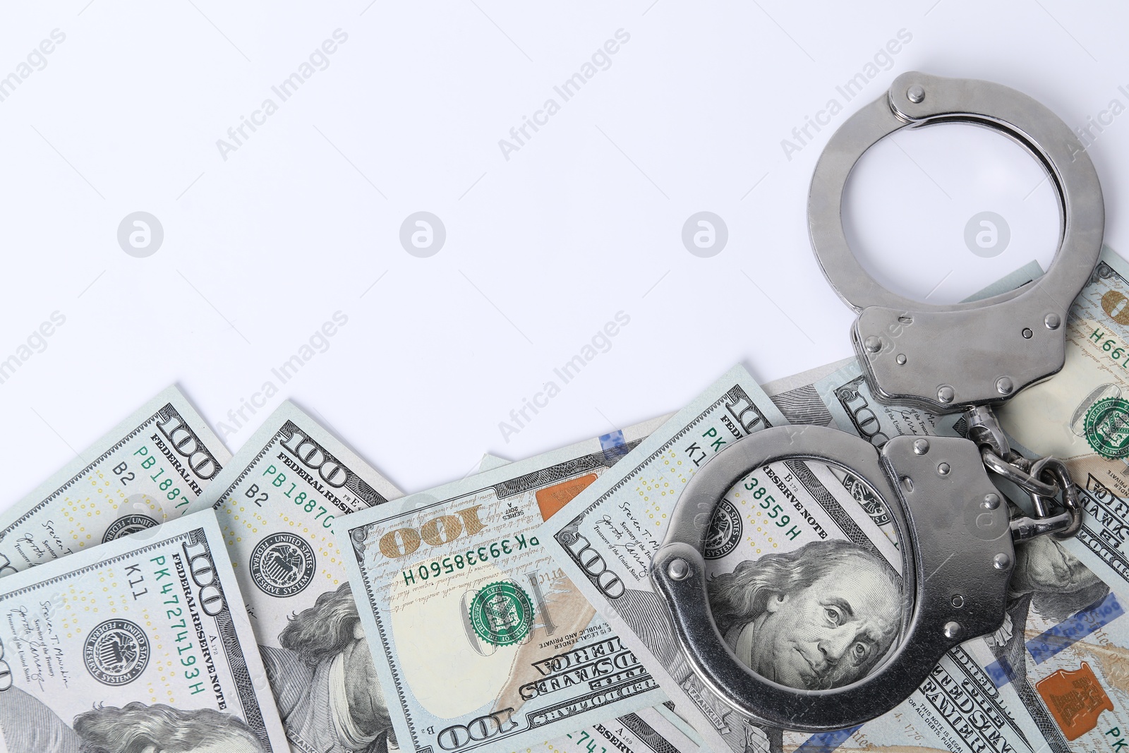 Photo of Corruption concept. Handcuffs and dollar banknotes on white background, top view