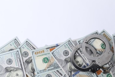 Photo of Corruption concept. Handcuffs and dollar banknotes on white background, top view