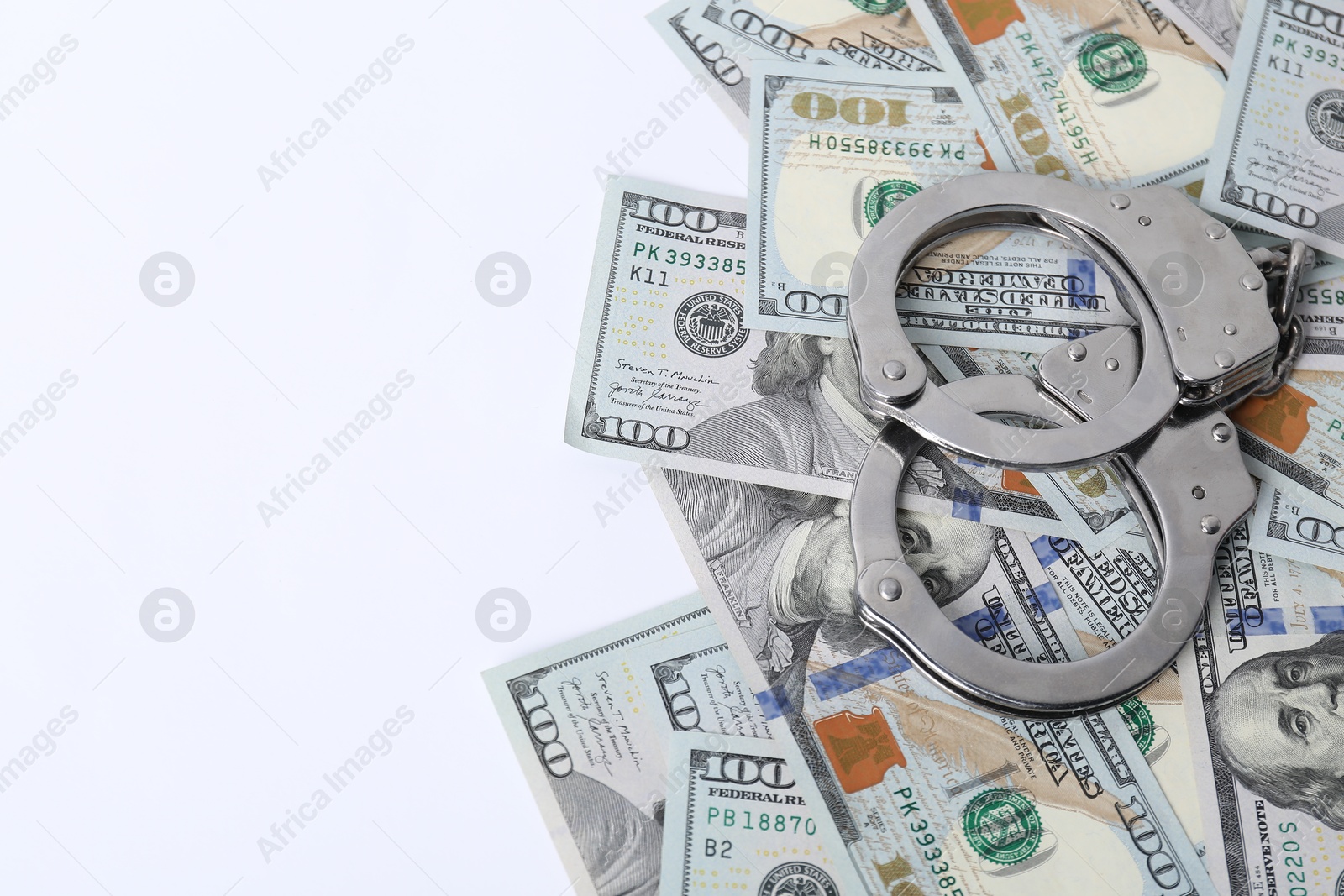 Photo of Corruption concept. Handcuffs and dollar banknotes on white background, above view. Space for text