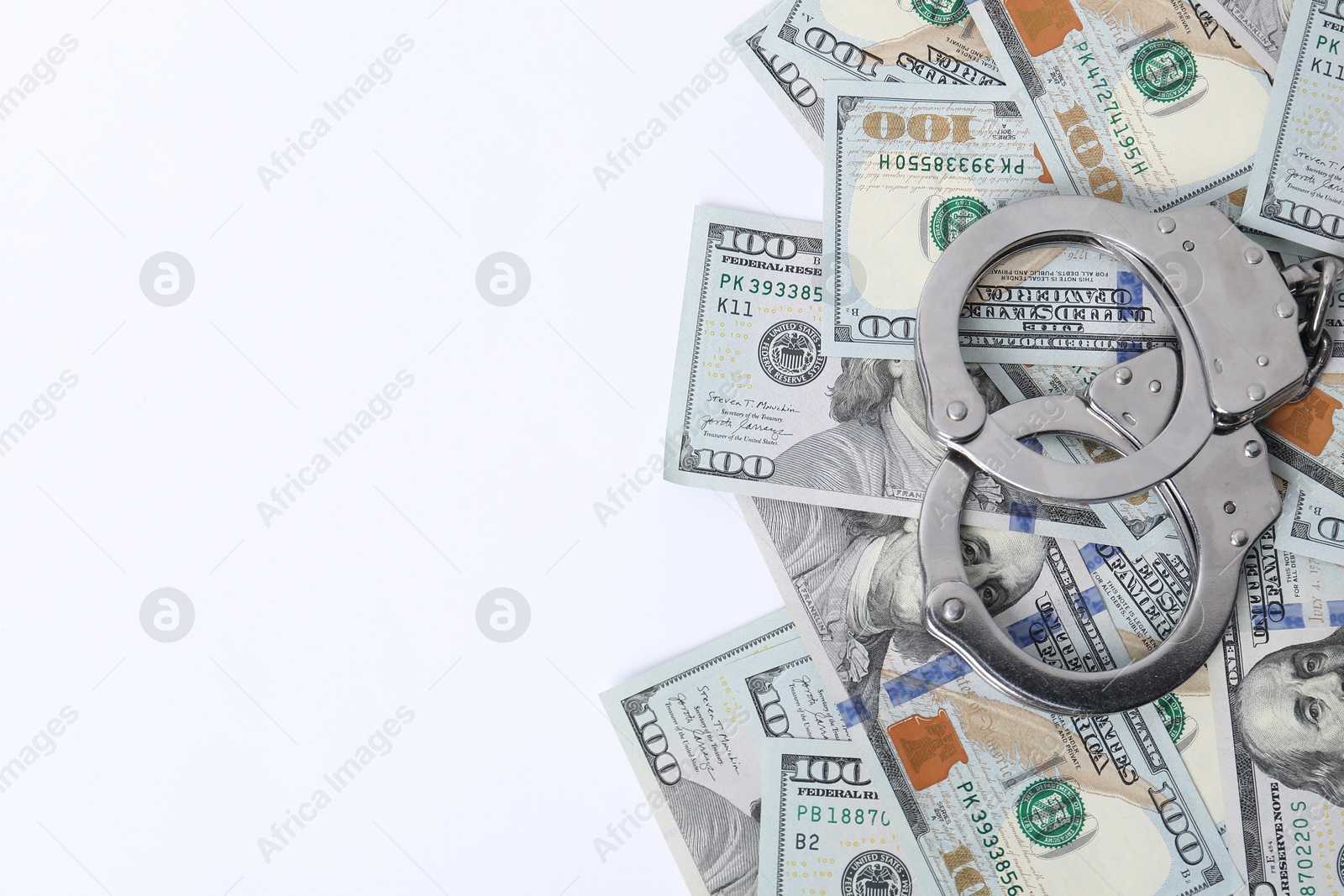 Photo of Corruption concept. Handcuffs and dollar banknotes on white background, top view. Space for text