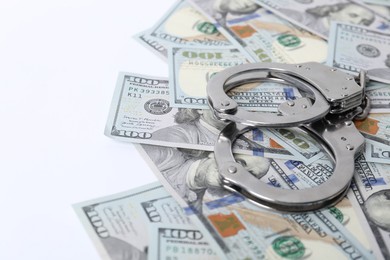 Photo of Corruption concept. Handcuffs and dollar banknotes on white background, closeup