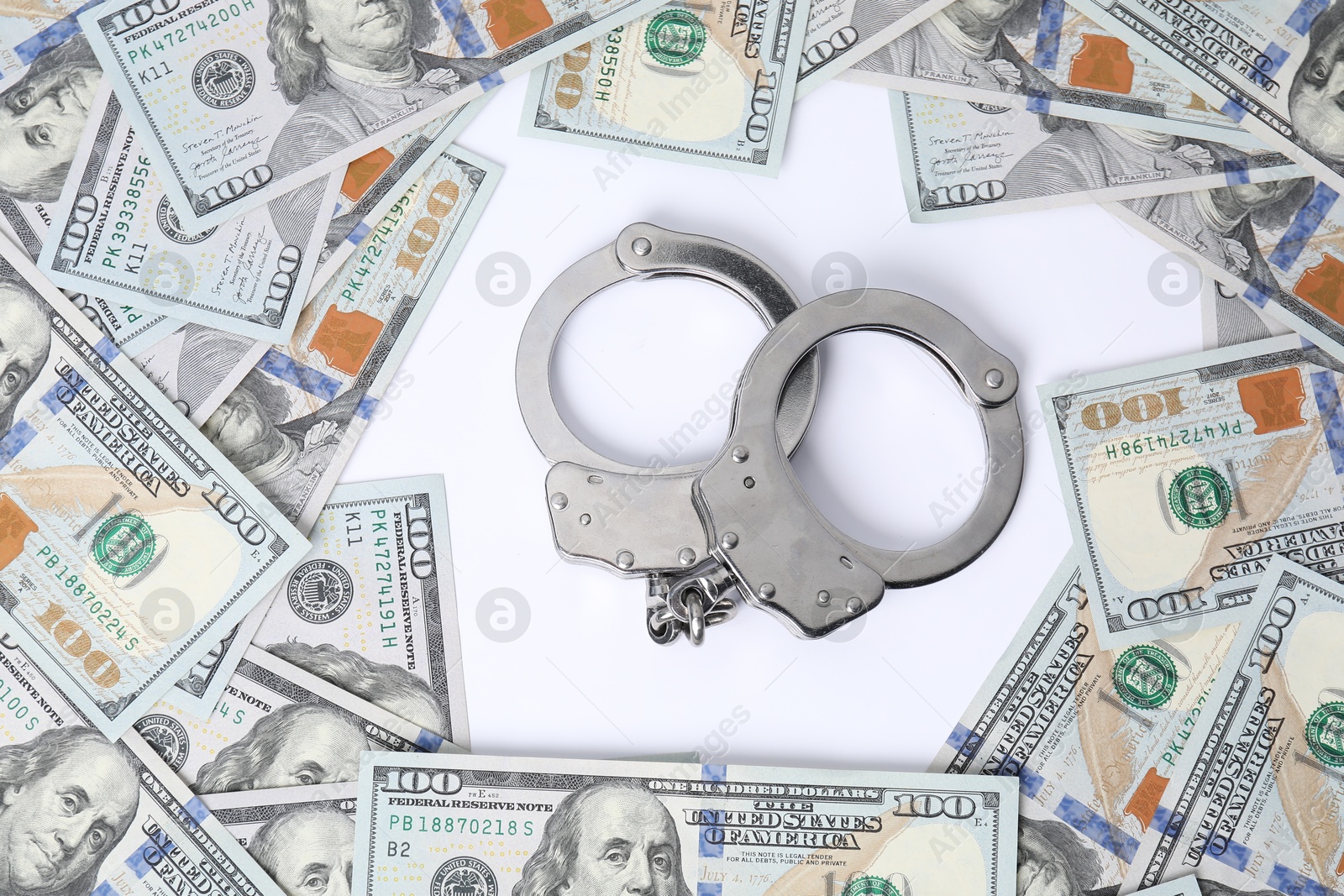 Photo of Corruption concept. Handcuffs and dollar banknotes on white background, top view