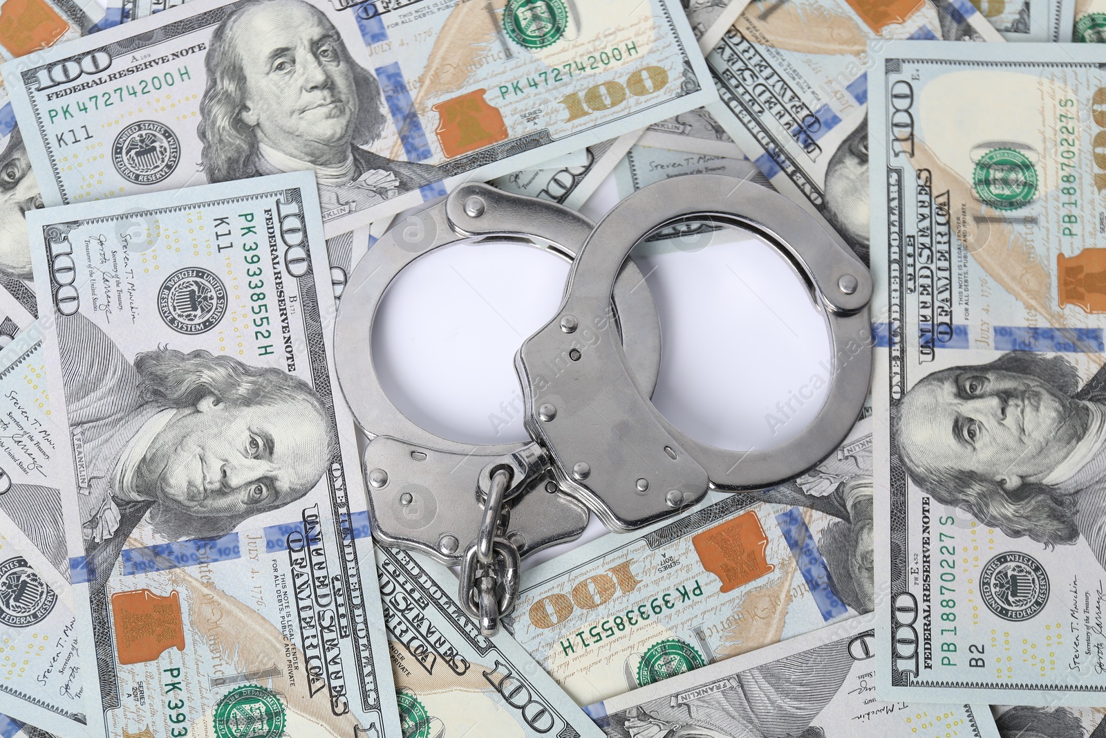 Photo of Corruption concept. Handcuffs and dollar banknotes on white background, top view