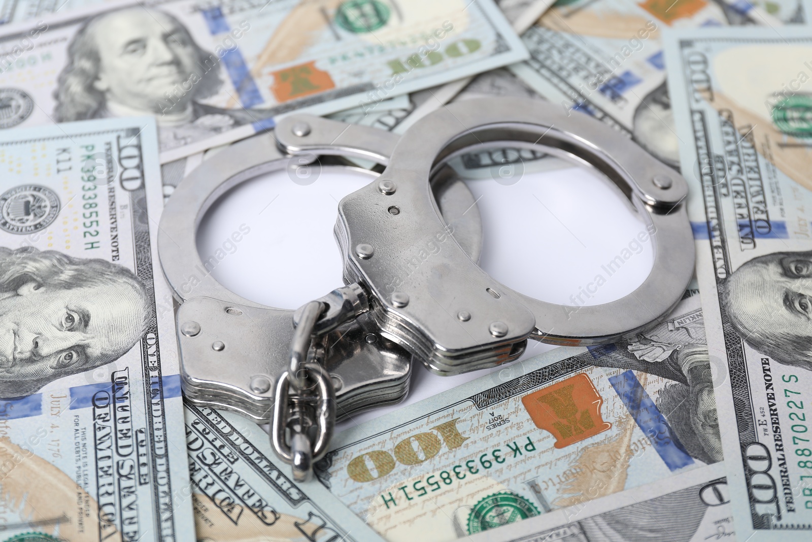 Photo of Corruption concept. Handcuffs and dollar banknotes on white background, closeup