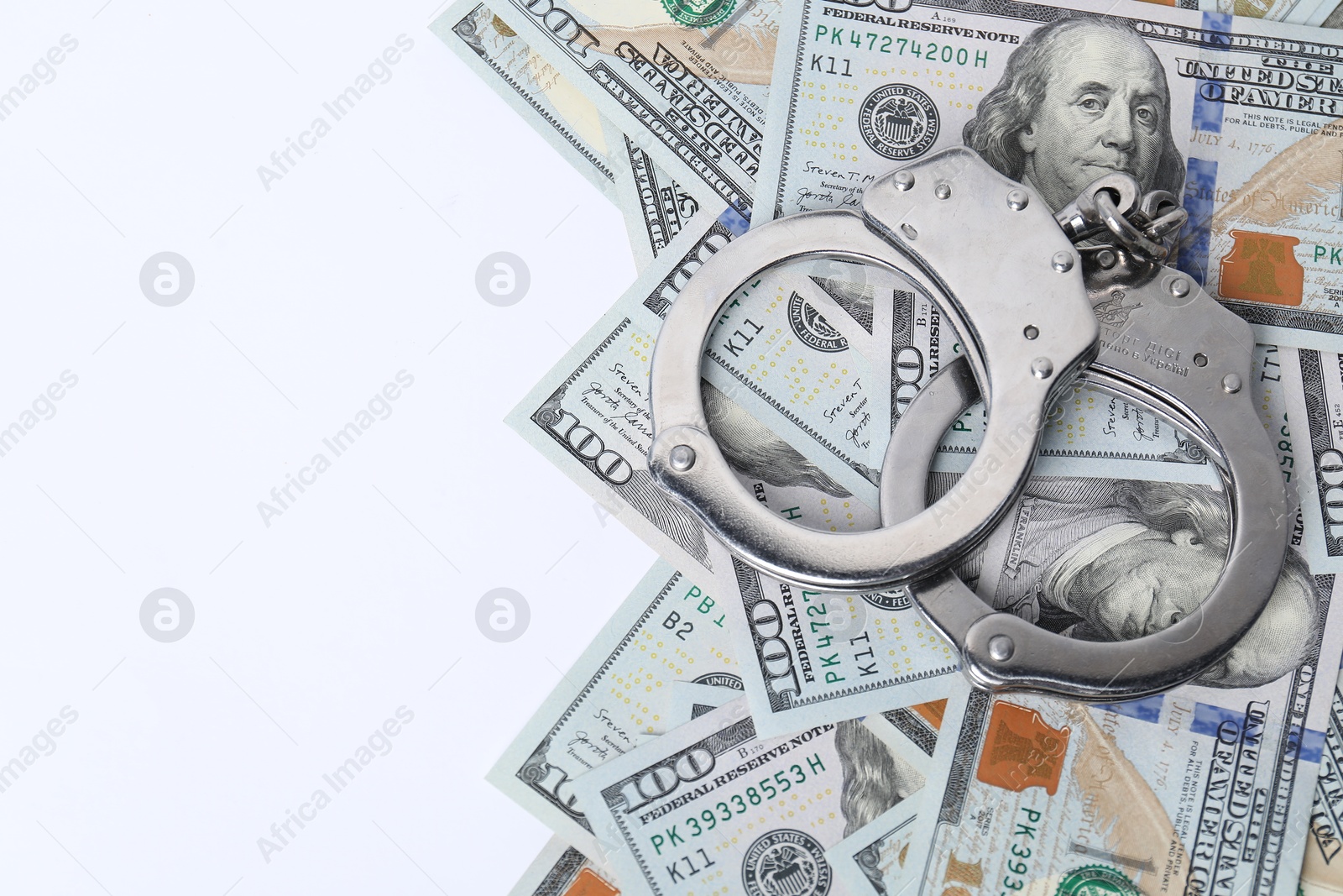 Photo of Corruption concept. Handcuffs and dollar banknotes on white background, top view. Space for text