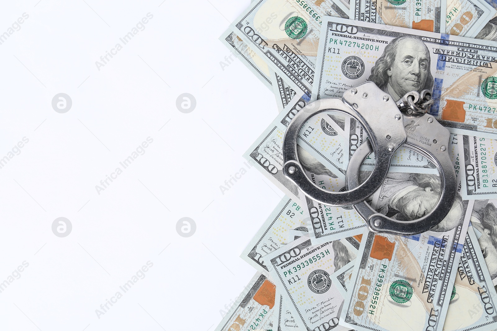 Photo of Corruption concept. Handcuffs and dollar banknotes on white background, top view. Space for text