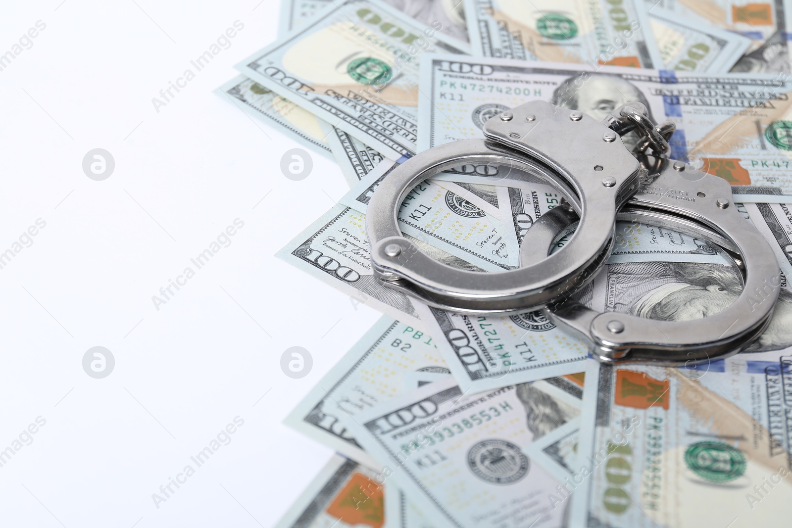 Photo of Corruption concept. Handcuffs and dollar banknotes on white background, closeup. Space for text