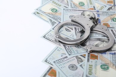 Photo of Corruption concept. Handcuffs and dollar banknotes on white background, closeup. Space for text