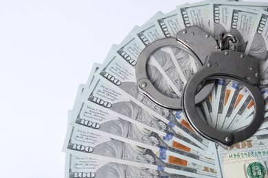 Photo of Corruption concept. Handcuffs and dollar banknotes on white background, above view