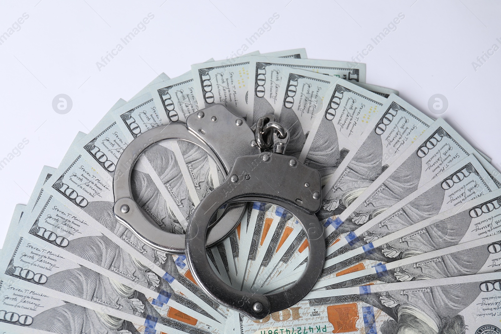 Photo of Corruption concept. Handcuffs and dollar banknotes on white background, top view