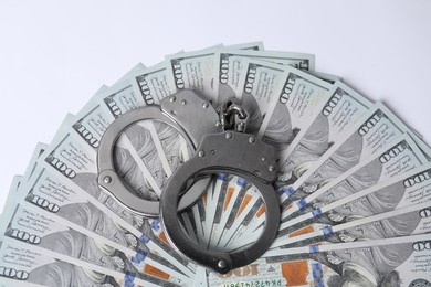 Photo of Corruption concept. Handcuffs and dollar banknotes on white background, top view