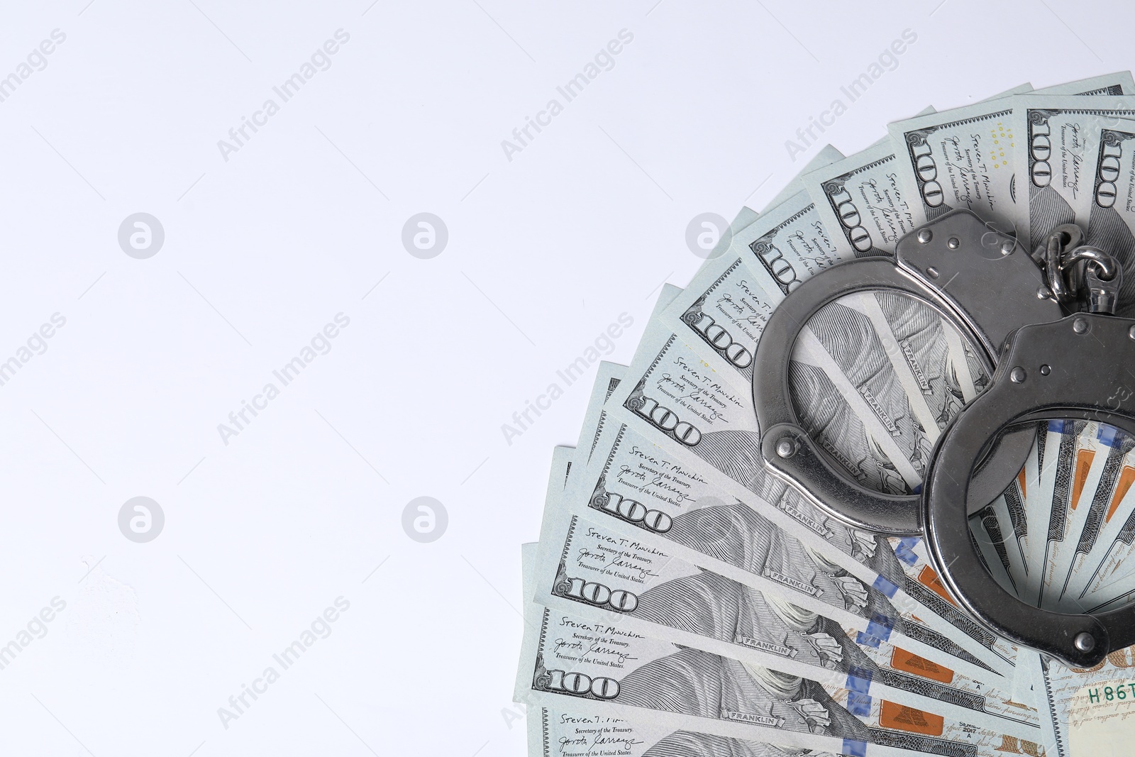 Photo of Corruption concept. Handcuffs and dollar banknotes on white background, top view. Space for text