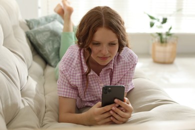 Photo of Beautiful teenage girl using smartphone on sofa at home