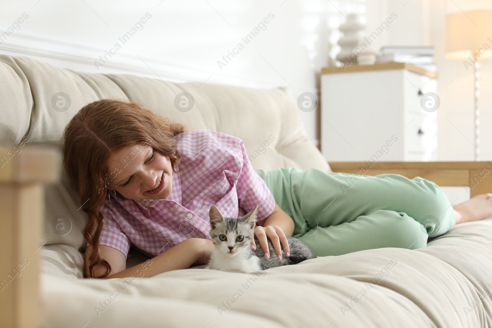 Photo of Beautiful teenage girl with cute cat on sofa at home