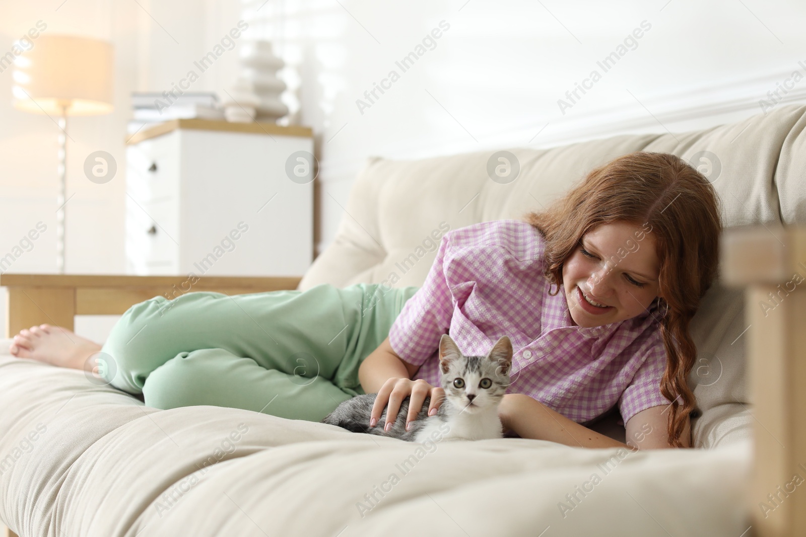 Photo of Beautiful teenage girl with cute cat on sofa at home