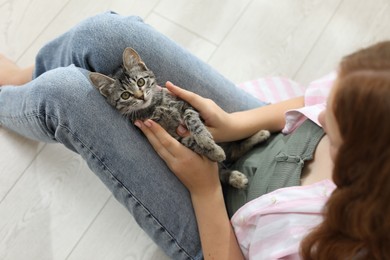 Photo of Teenage girl with cute cat on floor indoors, top view