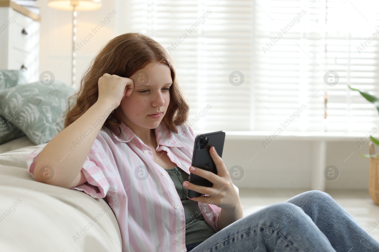 Photo of Beautiful teenage girl using smartphone on floor at home