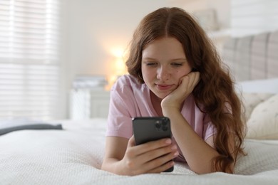 Photo of Beautiful teenage girl using smartphone on bed at home