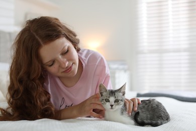 Beautiful teenage girl with cute cat on bed at home