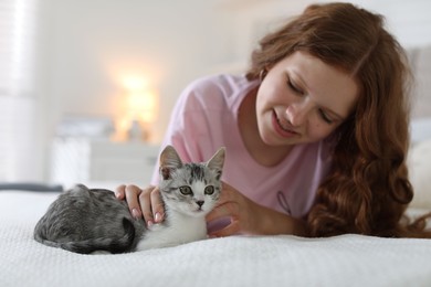 Beautiful teenage girl with cute cat on bed at home, selective focus