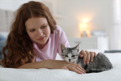 Beautiful teenage girl with cute cat on bed at home, selective focus