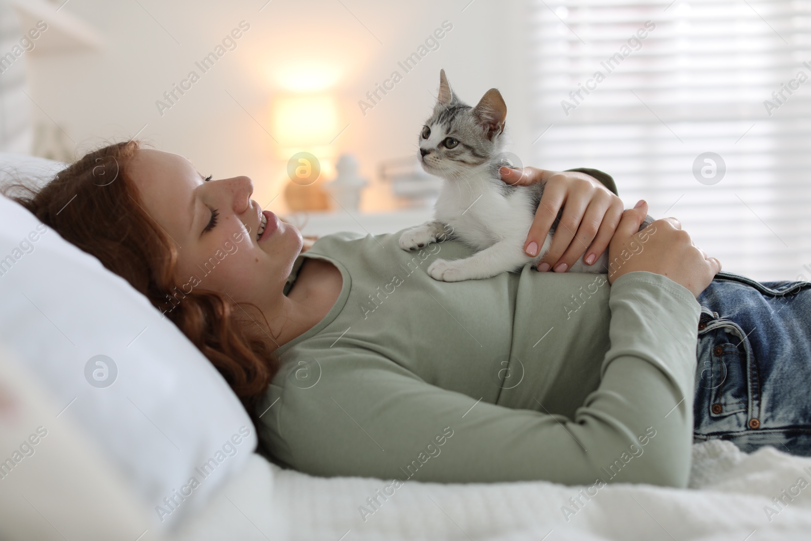 Photo of Beautiful teenage girl with cute cat on bed at home