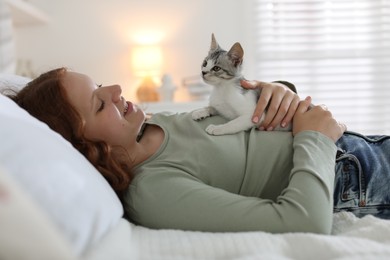 Beautiful teenage girl with cute cat on bed at home