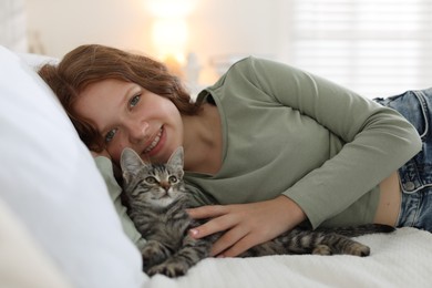 Beautiful teenage girl with cute cat on bed at home