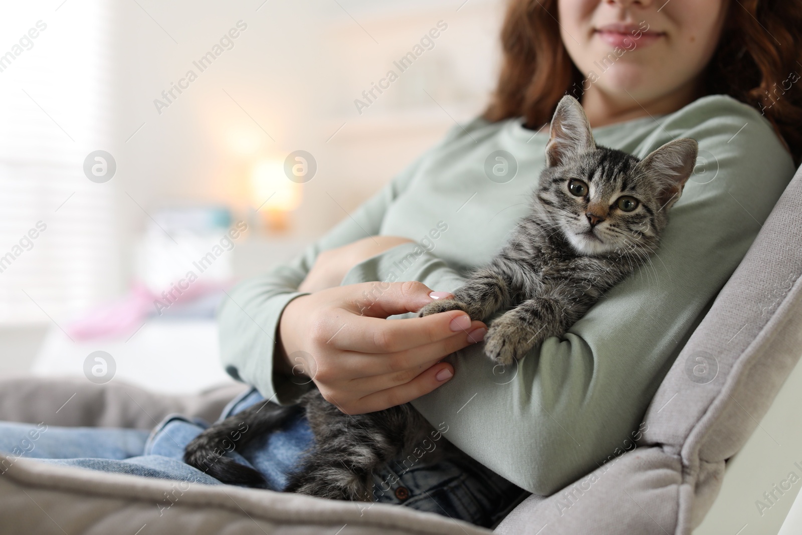 Photo of Teenage girl with cute cat on sofa at home, closeup