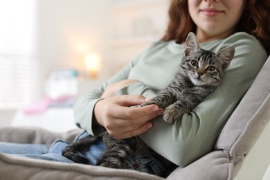 Photo of Teenage girl with cute cat on sofa at home, closeup