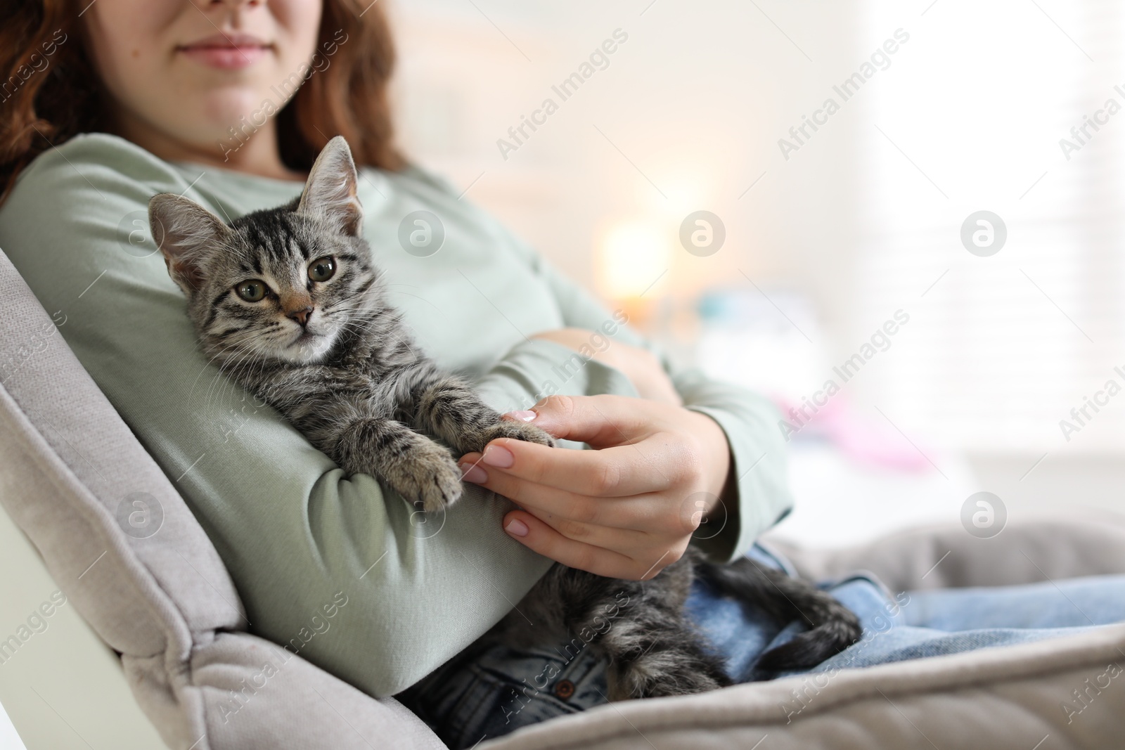 Photo of Teenage girl with cute cat on sofa at home, closeup