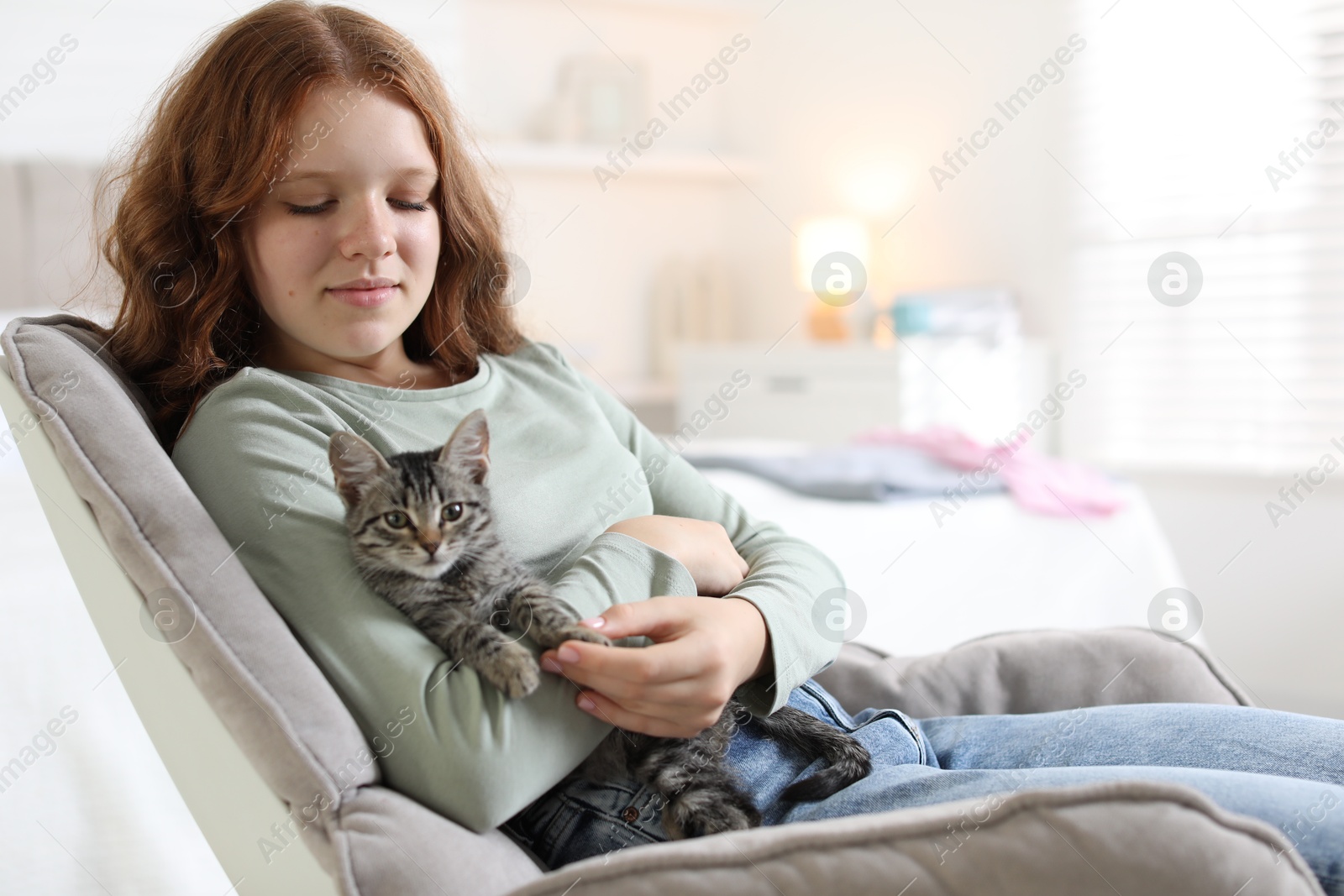 Photo of Beautiful teenage girl with cute cat on sofa at home