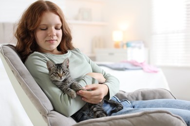 Photo of Beautiful teenage girl with cute cat on sofa at home