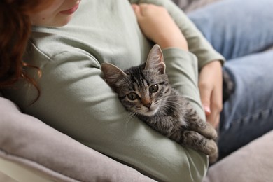 Teenage girl with cute cat on sofa at home, closeup