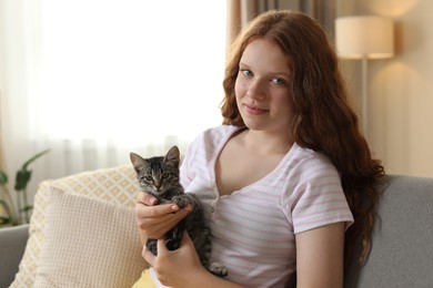 Photo of Beautiful teenage girl with cute cat on sofa at home