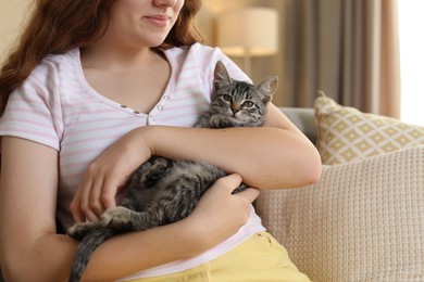 Photo of Teenage girl with cute cat on sofa at home, closeup