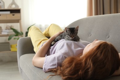 Photo of Teenage girl with cute cat on sofa at home