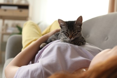 Photo of Teenage girl with cute cat on sofa at home, closeup