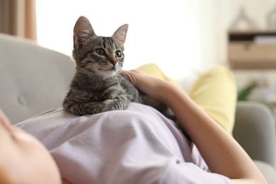 Teenage girl with cute cat on sofa at home, closeup