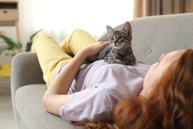 Photo of Teenage girl with cute cat on sofa at home