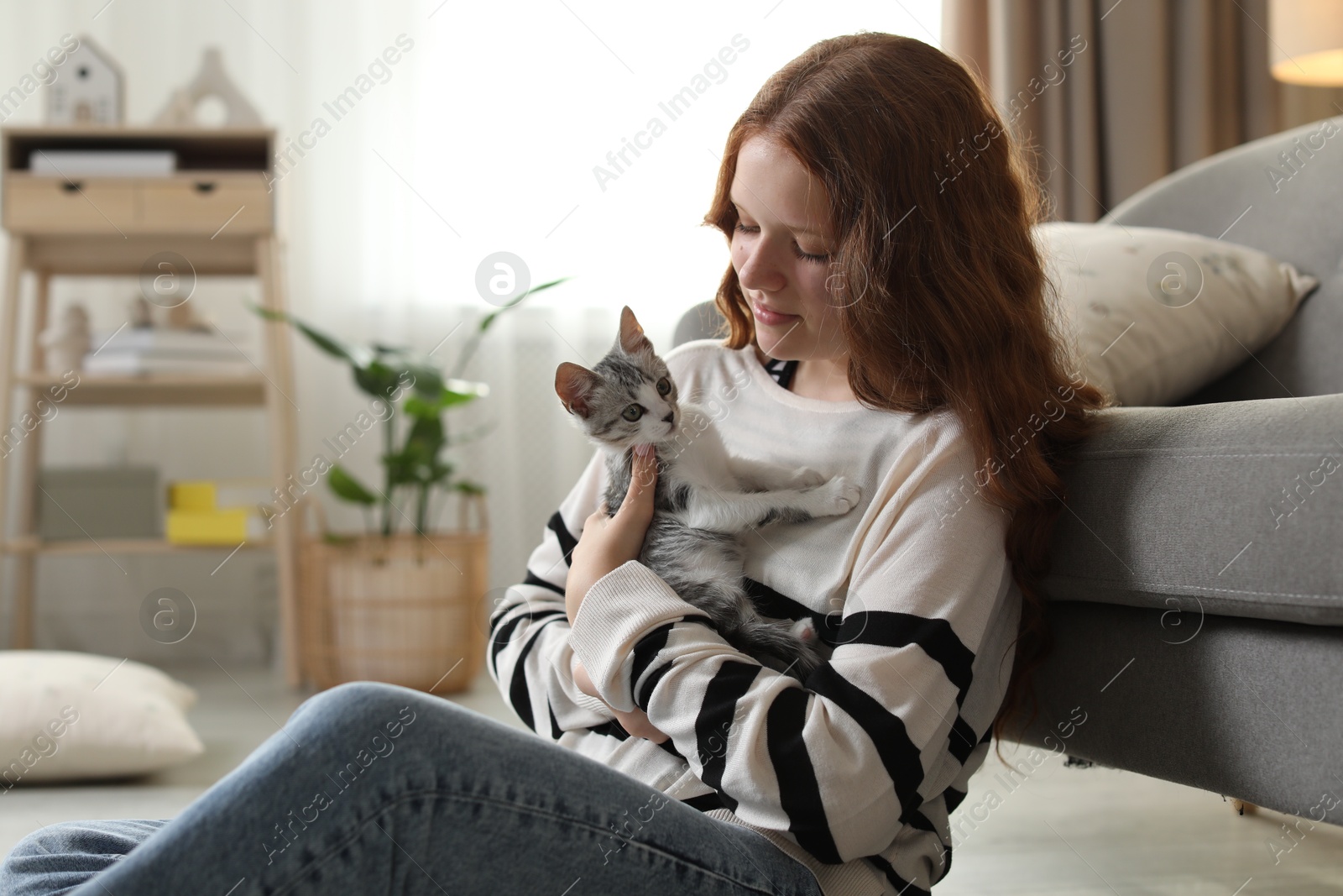 Photo of Beautiful teenage girl with cute cat on floor at home