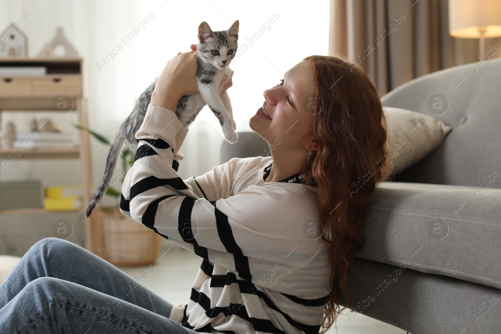 Photo of Beautiful teenage girl with cute cat on floor at home