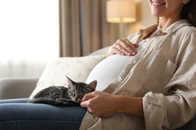 Photo of Pregnant woman with cute cat sleeping at home, closeup