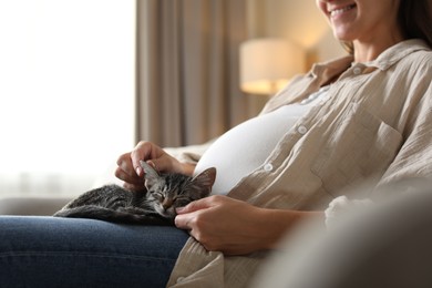 Pregnant woman with cute cat sleeping at home, closeup